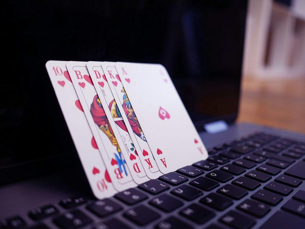 Escalera real de corazones apoyada sobre el teclado de un portátil